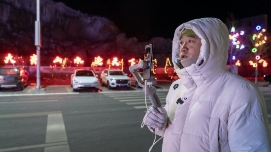 在吉林市阿什哈達霧凇觀景帶，霧凇播報員正在直播。新華社記者 李典 攝