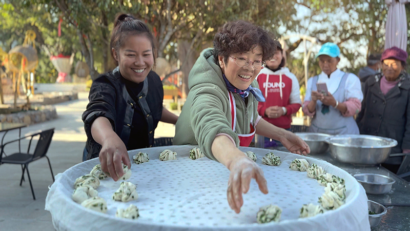 【2】旅居者趙發(fā)英（圖左二）教曼海村村民做花卷。陶思源-攝